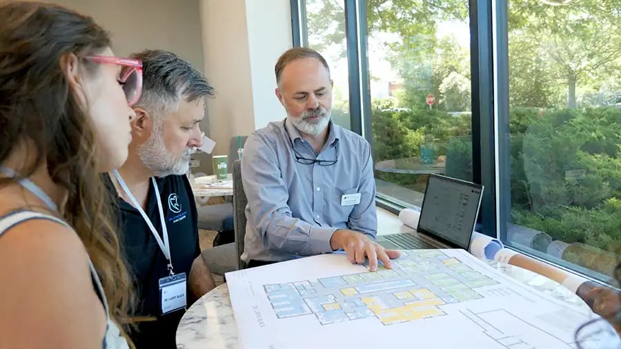 a dentist reviews a floor plan with a designer