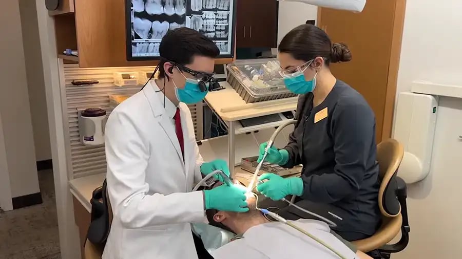 A dentist and assistant performing four-handed dentistry.