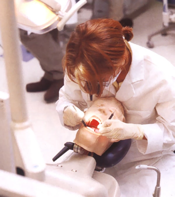 dental student hunched over a practice dummy
